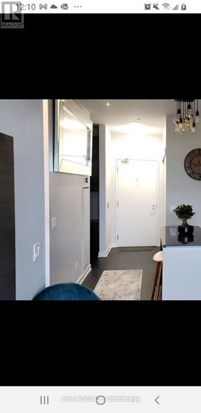 Toronto (Niagara) condo for rent - A modern interior with a white door and a round mirror on the wall.