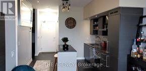 Toronto (Niagara) condo for rent - A modern kitchen with a bar area and a clock on the wall.
