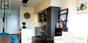 Toronto (Niagara) condo for rent - A living room with a couch, a chair, a cabinet, and a clock on the wall.