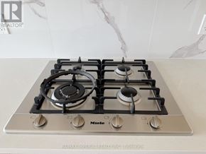 Toronto (Bayview Village) condo for rent - A gas stove with a silver finish and black knobs is on a marble countertop.