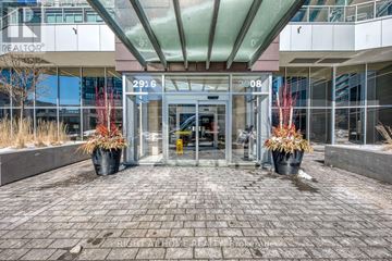 Vaughan (Concord) condo for rent - The image shows the front of a REALTOR® building with a glass entrance and two large planters with red plants.