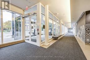 Toronto (Bayview Village) condo for rent - A hallway with a carpeted floor, glass doors, and a wall with a black and white pattern.