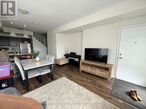 Pickering (Woodlands) townhouse for rent - A living room with a television, a dining table, and a kitchen area in the background.