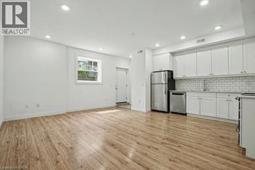 Waterloo townhouse for rent - A kitchen with white cabinets and a wooden floor.