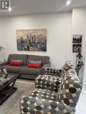 Pickering (Liverpool) apartment for rent - A living room with a grey couch, a brown and white patterned chair, and a painting on the wall.