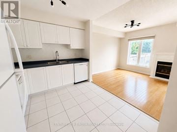 Whitby (Pringle Creek) townhouse for rent - A kitchen with white cabinets and a black counter top.