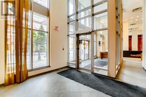 Mississauga (City Centre) condo for rent - A hallway with a black carpet and a glass door with a red exit sign.