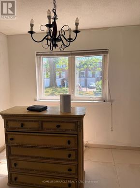 Toronto (Mount Olive-Silverstone-Jamestown) townhouse for rent - A chandelier hangs over a wooden chest of drawers in a room with a window.