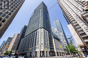 Toronto (Bay Street Corridor) condo for rent - A tall building with a glass facade stands in the middle of a city street.