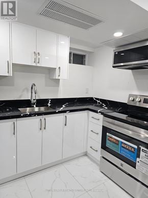 Toronto (Blake-Jones) apartment for rent - A modern kitchen with white cabinets and black countertops.