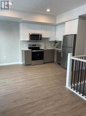 Guelph (Riverside Park) townhouse for rent - A kitchen with white cabinets and a wooden floor.