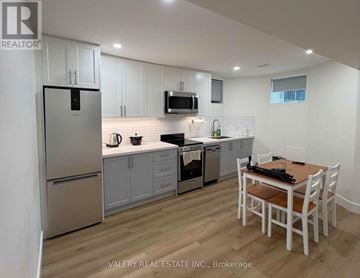 Toronto (Dovercourt-Wallace Emerson-Junction) fourplex for rent - A kitchen with white cabinets and a wooden table.