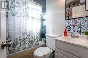 St. Catharines (Western Hill) apartment for rent - A bathroom with a toilet, sink, and shower curtain.