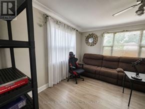 St. Catharines (Western Hill) apartment for rent - A room with a brown couch, a black chair, and a fan on the ceiling.