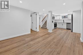 Niagara Falls (Chippawa) apartment for rent - A spacious room with wooden flooring and white walls, with a staircase leading to another level.