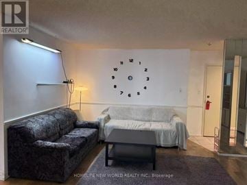 Toronto (Bay Street Corridor) condo for rent - A living room with a grey couch and a white bed with a grey blanket.
