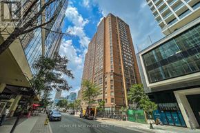 Toronto (Bay Street Corridor) condo for rent - A tall brown building stands in the middle of a city street.