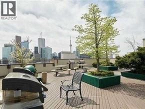 Toronto (Bay Street Corridor) condo for rent - A wooden deck with a table and chairs overlooking a city skyline.