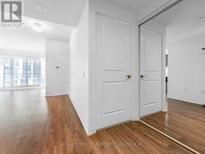 Toronto (Moss Park) condo for rent - A room with white walls and wooden floors, with a door on the left and a window on the right.
