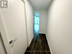 Vaughan (Vaughan Corporate Centre) condo for rent - A hallway with a door on the left and a window in the distance.