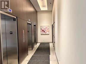 Milton (Co Coates) condo for rent - A hallway with elevators and a painting on the wall.