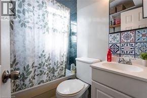 St. Catharines apartment for rent - A bathroom with a toilet, sink, and shower curtain.