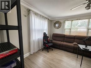St. Catharines apartment for rent - A room with a brown couch, a black chair, and a black shelf with a red box on it.