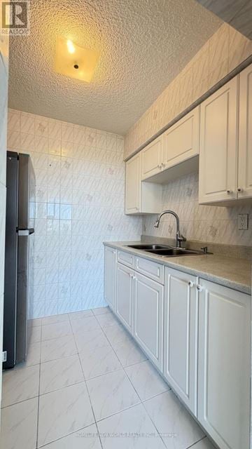 Toronto (Yorkdale-Glen Park) condo for rent - A kitchen with white cabinets and a black refrigerator.