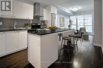 Toronto (Niagara) condo for rent - A modern kitchen with white cabinets and a wooden floor.
