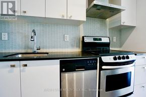 Toronto (Niagara) condo for rent - A kitchen with white cabinets and a black stove top oven.