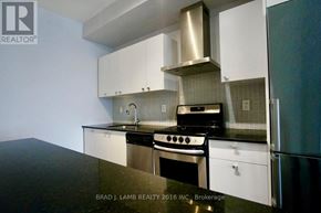 Toronto (Niagara) condo for rent - A modern kitchen with white cabinets and stainless steel appliances.