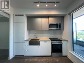 Toronto (South Parkdale) condo for rent - A modern kitchen with white cabinets and stainless steel appliances.