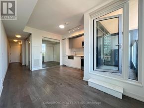 Toronto (South Parkdale) condo for rent - A spacious room with a large window and wooden flooring.