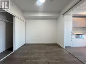 Toronto (South Parkdale) condo for rent - Empty room with white walls and wooden floor.
