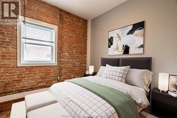 Chatham apartment for rent - A bedroom with a brick wall and a bed with a green blanket.