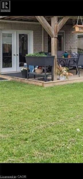 Guelph apartment for rent - A patio with a table and chairs is surrounded by a grassy area.