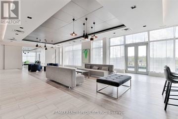 Mississauga (Central Erin Mills) condo for rent - A spacious living room with a grey sofa and a black chair.