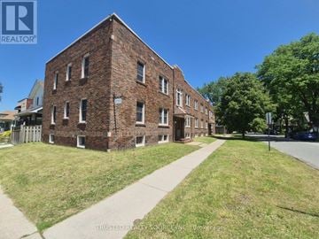 Windsor multi-family for rent - A brick building with a grassy area in front and a sidewalk leading to the entrance.
