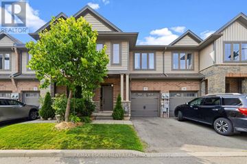 Hamilton (Lakeshore) townhouse for rent - A large, well-maintained house with a tree in front and two cars parked in the driveway.