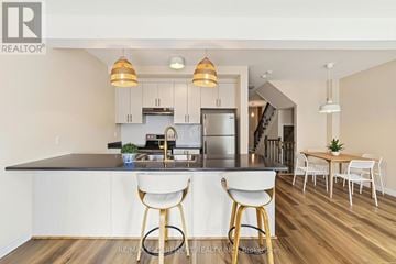 Hamilton (Lakeshore) townhouse for rent - A modern kitchen with white cabinets and a wooden island.
