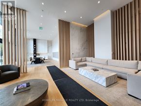 Mississauga (Cooksville) condo for rent - A modern living room with a black leather chair and a coffee table with a book on it.