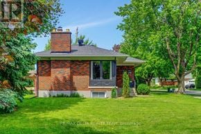Ottawa apartment for rent - A house with a brick facade and a grey roof is surrounded by greenery.