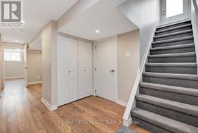 Ottawa apartment for rent - A staircase with a carpeted runner leads up to a landing with a white door and two white cabinets.