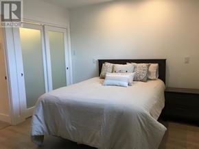 St.John's multi-family for rent - A bed with a white comforter and two pillows sits in a bedroom with a white door and a black headboard.