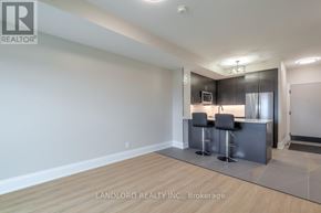 Oakville (Jm Joshua Meadows) condo for rent - A modern kitchen with a bar stool and a fridge.