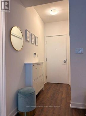 Toronto (Niagara) condo for rent - A hallway with a white door, a round mirror, and a wall with pictures.