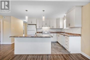 Cornwall triplex for rent - A kitchen with white cabinets and a marble countertop.