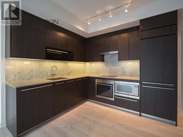 Toronto (Waterfront Communities) condo for rent - A kitchen with dark wood cabinets and a marble backsplash.
