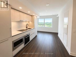 Toronto (North St. James Town) condo for rent - A modern kitchen with white appliances and wooden floors.