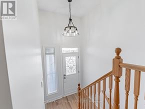 Toronto (Bendale) townhouse for rent - A white hallway with a wooden staircase and a chandelier.